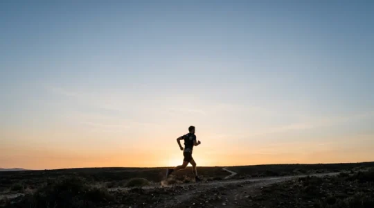 A powerful wide-angle composition showing a human figure in motion against vast negative space, symbolizing the relationship between cardiovascular capacity and longevity