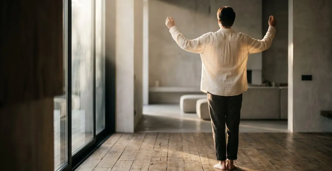 Person standing near a large window with morning sunlight streaming in, creating dramatic natural lighting and long shadows