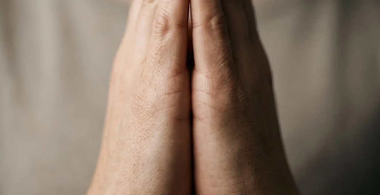 Extreme close-up macro shot of a person's hands in a calm gesture with visible skin texture and soft directional lighting